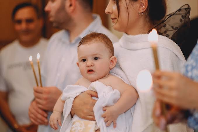 Baby held by family at a baptism